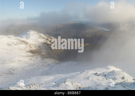 Vista da vicino il vertice di ben VORLICH UN MUNRO verso la coperta di neve piccole colline e LOCH ARKLET al di là delle Alpi a Arrochar Foto Stock