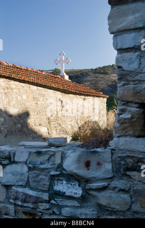 Vecchia Cappella con bianchi barrare oltre il cielo blu visto attraverso la rottura vecchio muro di pietra in alto Lefkara, Cipro del Sud. Foto Stock