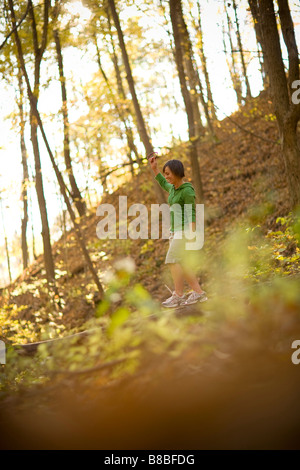 Donna in equilibrio su caduto albero tronco nel bosco Foto Stock