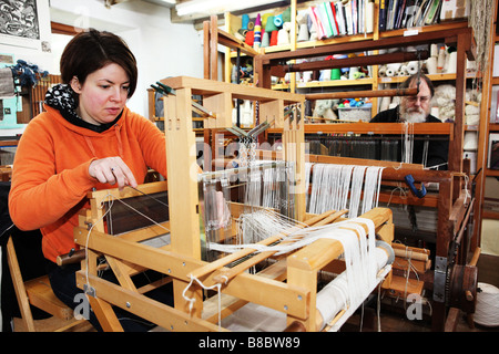 Due tessitori a mano lavorando a piccoli in legno tradizionali macchine di tessitura in un piccolo studio di tessili nel Regno Unito in fabbrica Foto Stock