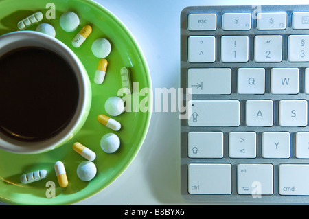 Il doping a lavoro. Caffè compresse e pillole su un piattino accanto alla tastiera di un computer. Foto Stock