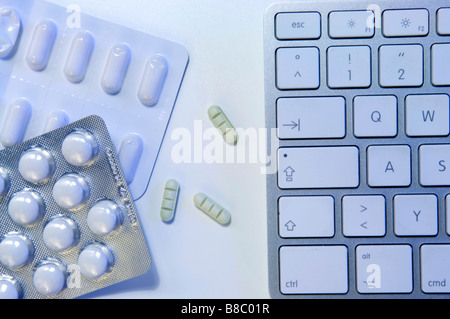 Il doping a lavoro. Compresse e pillole su un piattino accanto alla tastiera di un computer. Foto Stock