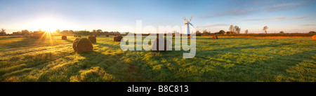 Sunrise su un campo di balle di fieno di fronte Thurne Mulino a vento sulla Norfolk Broads Foto Stock