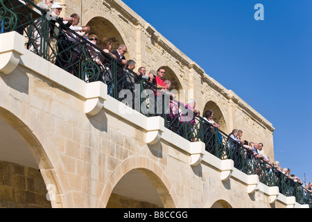 Tourist guardando il fuoco del mezzogiorno-day gun da Upper Barrakka Gardens. Batteria a salve, Valletta, Malta. Foto Stock