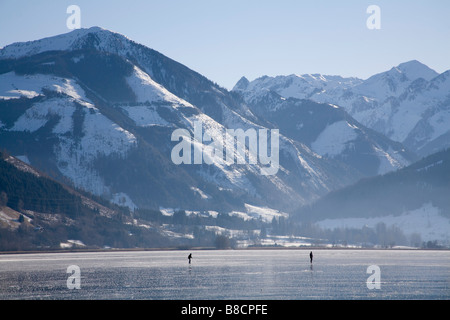 Zell am See Austria UE gennaio vista in lontananza due persone pattinaggio sulla congelati lago Zeller See Foto Stock