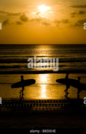 Surfisti sulla spiaggia di Kuta Beach, Bali, al tramonto Foto Stock