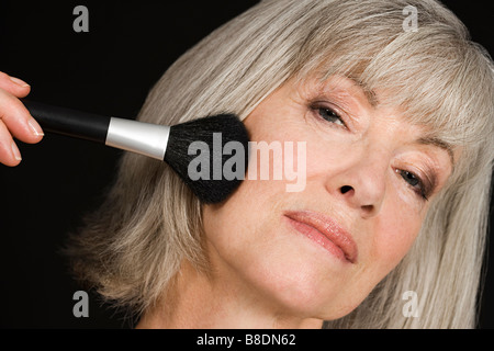 Donna senior di applicare il make up Foto Stock