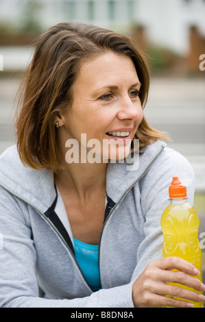 Donna matura con una bottiglia di succo di arancia Foto Stock