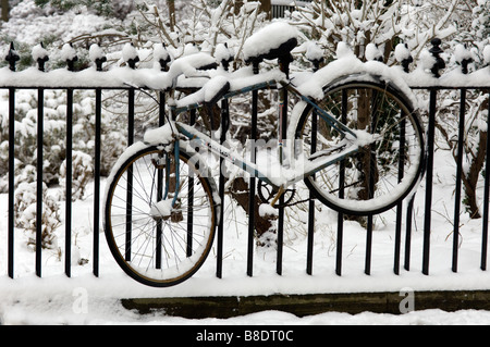 Una bicicletta ricoperta di neve ormeggiato a Victorian ringhiere in Brunswick Square Hove East Sussex Foto Stock