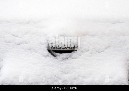 Nissan auto logo produttore ricoperta di neve e ghiaccio. Foto Stock