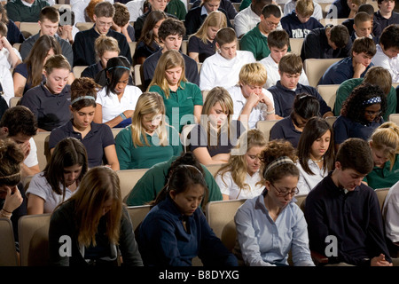 Gli studenti in un auditorium presso un privato scuola cristiana con la loro testa inchinata in preghiera Foto Stock