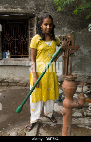 Ragazza adolescente lavora una pompa a mano per attingere acqua da un pozzo. Hazira, Surat, Gujarat. India. Foto Stock