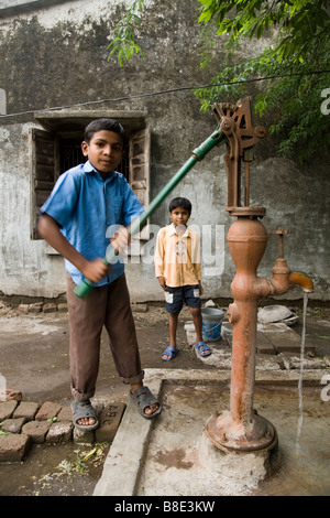 Ragazzo lavorando una pompa a mano per attingere acqua da un pozzo. Hazira, Surat, Gujarat. India. Foto Stock