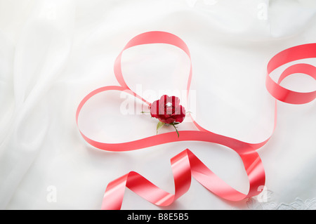 Forma di cuore creato utilizzando un nastro rosso single rose nel cuore Foto Stock