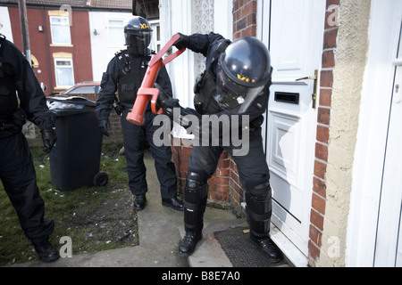 Ufficiali dal quartiere Bransholme Policing Team utilizzano un ariete per immettere una proprietà per la ricerca di farmaci, Hull, Regno Unito Foto Stock