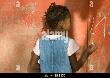 Ragazza senegalese la scrittura su una parete con un gessetto sulla Ile de Goree in Senegal Africa occidentale Foto Stock