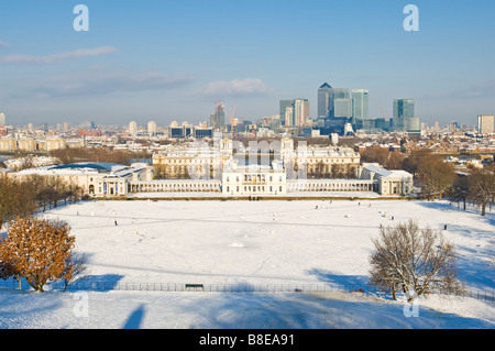 La vista dalla cima della collina di Greenwich Park si affaccia Marittime Greenwich e Canary Wharf con neve sul terreno. Foto Stock