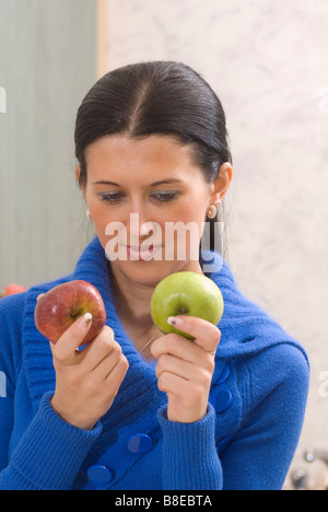 Donna scegliendo tra il verde e le mele rosse Foto Stock