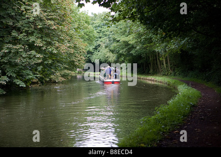 Due uomini sterzare una stretta barca lungo la Bridgewater Canal e di negoziare una curva nel loro viaggio Foto Stock