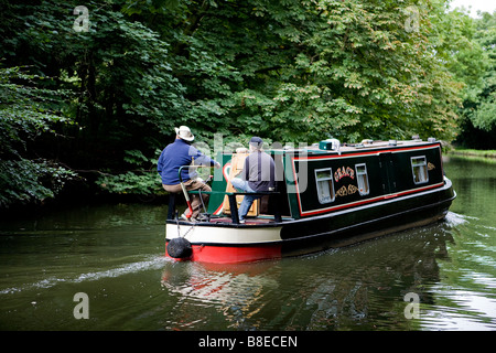 Due uomini sterzare una stretta barca lungo la Bridgewater Canal e di negoziare una curva nel loro viaggio Foto Stock