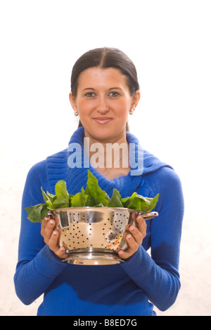 Donna che mantiene un colapasta di spinaci Foto Stock