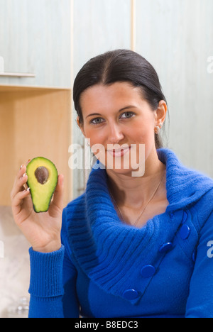 Bella giovane donna tenendo un dimezzato frutto di Avocado Foto Stock