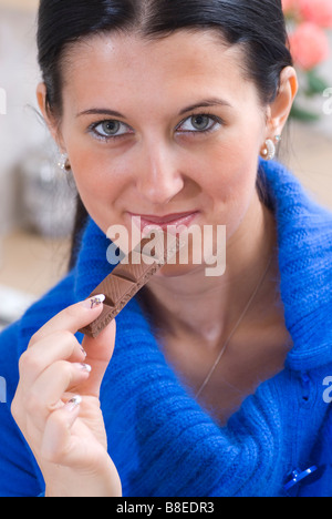 Bella giovane donna mangiando cioccolato bar Foto Stock