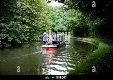 Due uomini sterzare una stretta barca lungo la Bridgewater Canal e di negoziare una curva nel loro viaggio Foto Stock