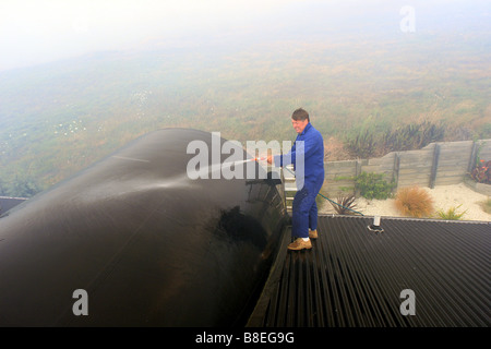 L'uomo il lavaggio il suo tetto di inumidire e proteggere la casa come un bushfire chiude in su la sua proprietà in Nuova Zelanda Foto Stock