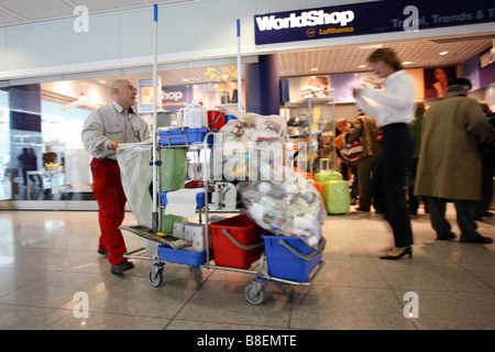 Pulitore a piedi attraverso la sala di attesa dell'aeroporto di Monaco di Baviera, Germania Foto Stock