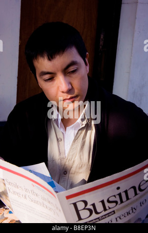 Giovane uomo leggendo il giornale aziendale Foto Stock