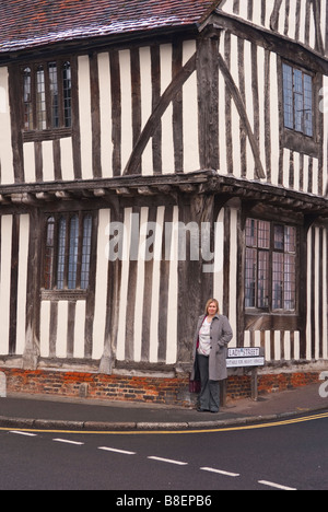 Una donna in piedi su un angolo della strada in Lady Street a Lavenham,Suffolk, Regno Unito Foto Stock