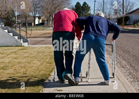 Due anziani anziani a piedi utilizzando i camminatori, la donna lo scatto l'uomo, il senso dell'umorismo umorismo, uno dei quattro in serie Foto Stock