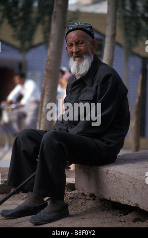 Vecchio Uighur uomo seduto fuori moschea Kashgar nello Xinjiang Cina Foto Stock