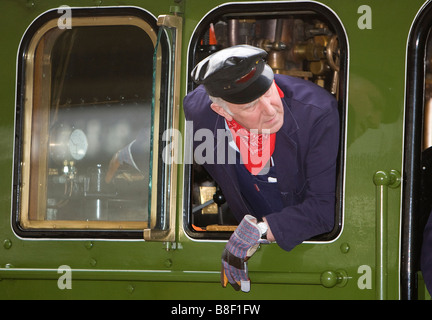 Il treno ingegnere driver guarda indietro dal pavimento di una classe di Peppe A1 motore a vapore come egli inverte a York Sta ferroviarie Foto Stock