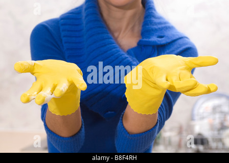 La donna in cucina giallo da indossare guanti di gomma Foto Stock