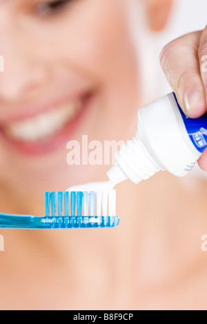 Donna mettendo il dentifricio su uno spazzolino da denti Foto Stock