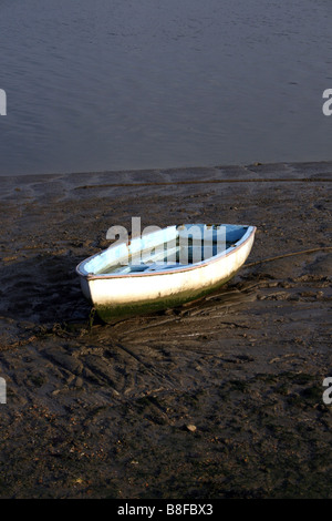 Una vecchia barca a remi a bassa marea su una spiaggia fangosa. Foto Stock