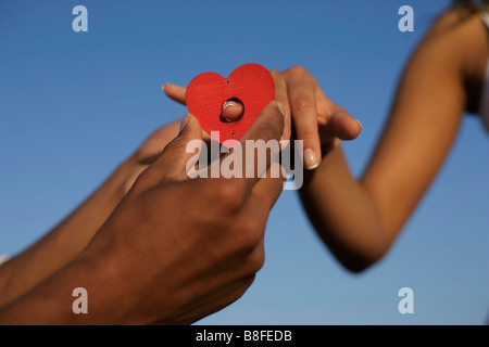 L'uomo mettendo a forma di cuore ad anello sulla donna del dito Foto Stock