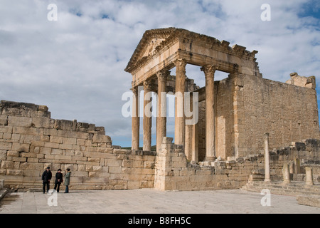 Tra Tunisia's rovine Romane è Dougga con la sua splendida Capitol. Tre i visitatori guardano le piccole nel forum accanto ad esso. Foto Stock