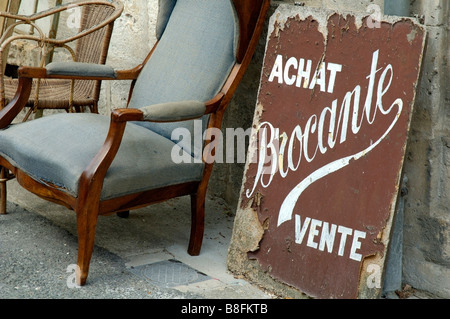 Vecchio weathered segno di antiquariato e una sedia al di fuori di un bric-a-brac shop, Borgogna, Francia. Foto Stock