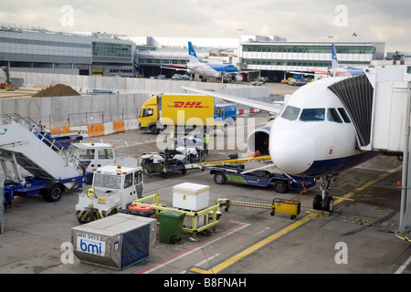 Movimentatori di bagagli e veicoli intorno a un aereo BMI sul tarmac al Terminal 1, aeroporto di Heathrow, Londra, Regno Unito Foto Stock