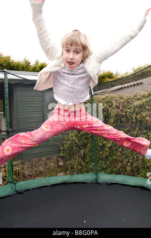 Un bambino di sei anni ragazza rimbalza su un trampolino. Foto Stock