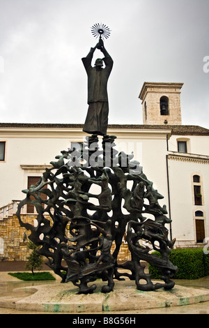 La scultura in bronzo di Padre Pio nel centro della città di San Giovanni Rotondo in Italia. Dietro di esso è la chiesa di San Leonardo. Foto Stock