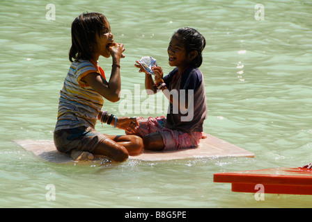 Moken bambini seduti sulla scheda di plastica godere mangiando snack, Koh Surin,PhangNga,nel sud della Thailandia. Foto Stock