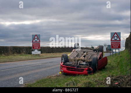 Car crash / auto rottamata di auto sportiva con ridurre i segni di velocità in background Foto Stock