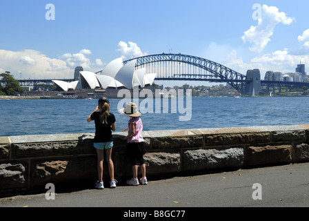 Due bambini (10 anni, 6 anni) guardando attraverso acqua a Sydney Opera House e Harbour Bridge. Sydney, Australia Foto Stock