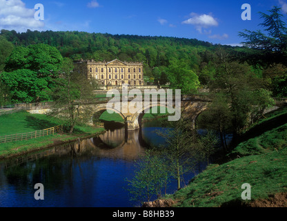 Chatsworth House - vista la grande casa di paese raggiunto da una pietra ponte ad arco sul fiume Derwent Foto Stock