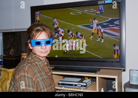 Donna che indossa gli occhiali 3D nella parte anteriore del TV con 3D Superbowl giocando sulla televisione Foto Stock