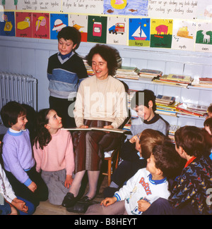 Insegnante che legge un libro agli alunni in una classe presso una scuola di villaggio rurale a Ffarmers Carmarthenshire Dyfed Wales UK educazione anni '1980 KATHY DEWITT Foto Stock